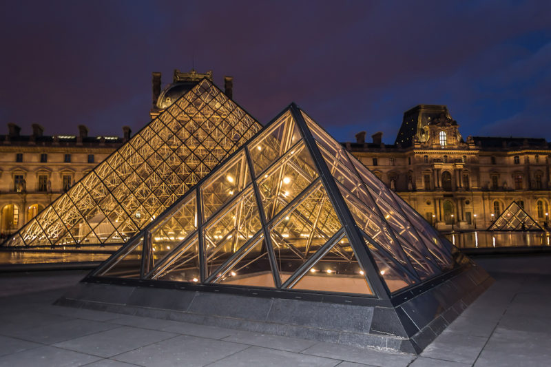What to see at the Louvre in 2 hours: the glass pyramids all lit up at night.