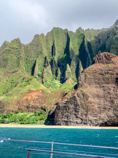 The Napali Coast of Hawaii has rigid green mountains and beautiful blue water. 