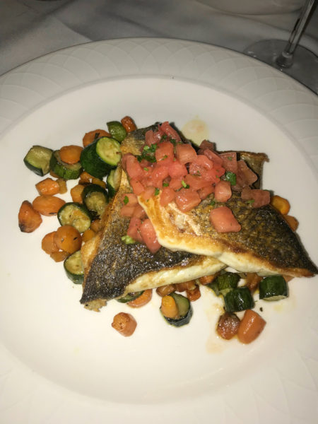 Bronzino fish served with small roasted vegetables.