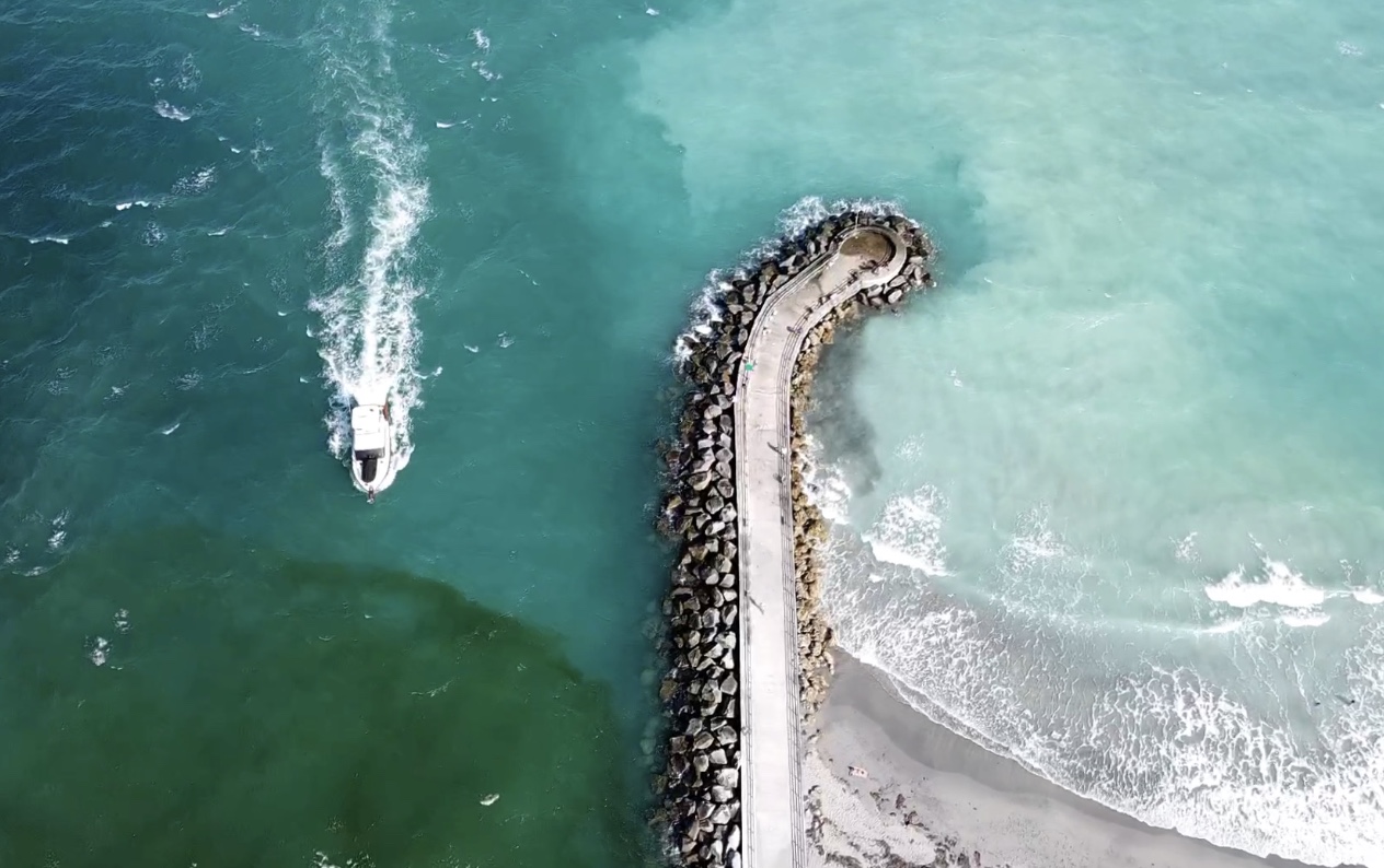 A drone shot of one of the beaches in Jupiter Florida as a boat goes through the inlet.