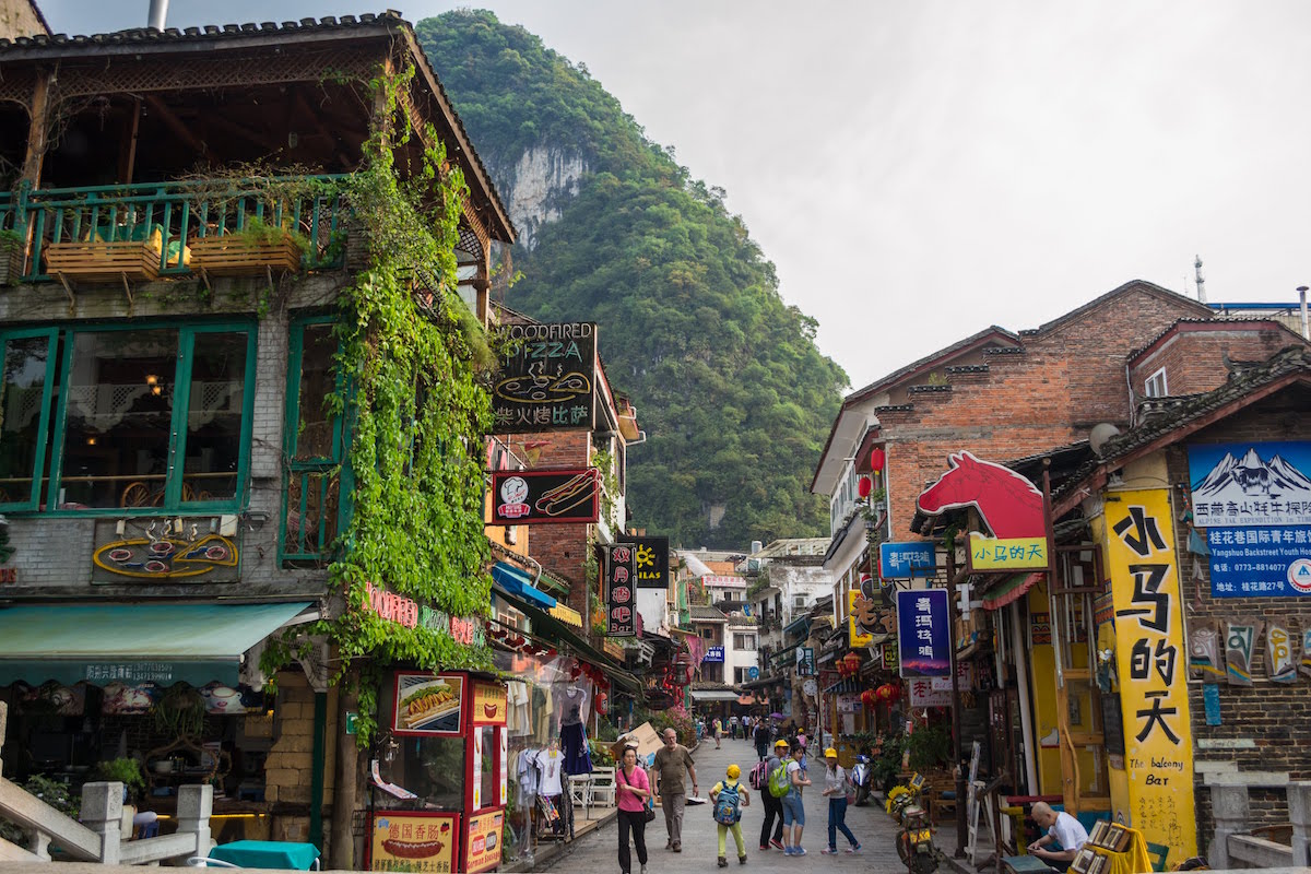 The town of Yangshuo, China has cute buildings and steep mountains behind it.