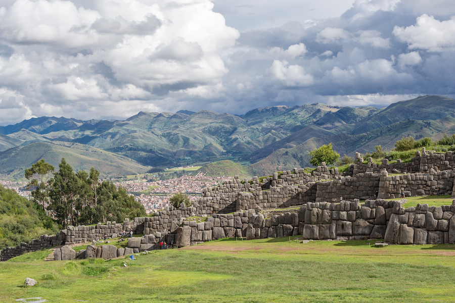 The Cusco ruins at Sacsayhuaman-a rock wall with the Andes mountains behind it.
