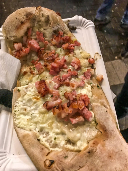Flammkuchen is a German snack of flatbread with creme fraiche, white cheese, bacon and onion.