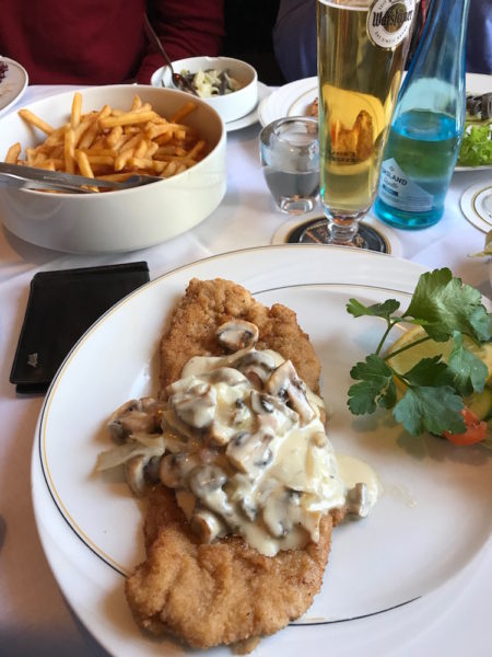 A plate of breaded schnitzel with a mushroom gravy on top.