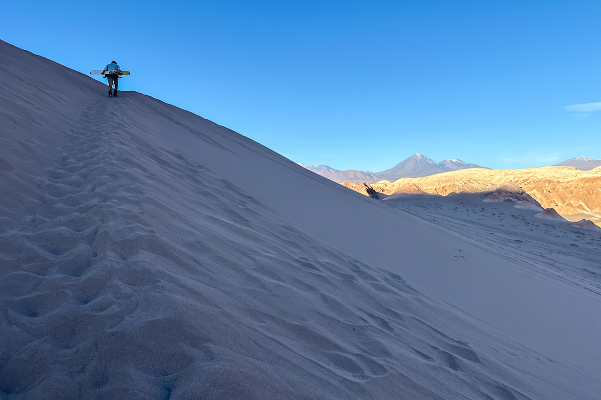 Hiking the sand dune while sandboarding in Chile.